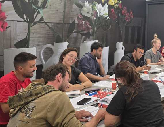 Deelnemers werken met schriften aan een lange tafel