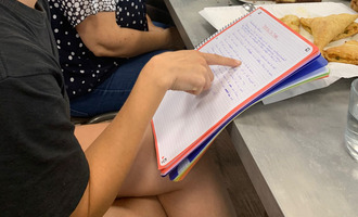 Een hand wijst naar tekst in een schrift